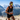 Man running on a mountain trail with snow-capped peaks in the background