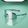 A pair of shield-style sunglasses with a large mirrored lens and turquoise and black arms, photographed on a smooth mint-green surface with a reflection below. The brand name 4KAVUD is visible on the lens and arm.